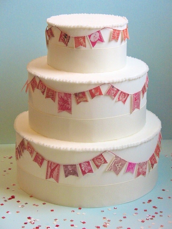 Vintage stamps are cut into flags and wrapped around wedding cake as garland