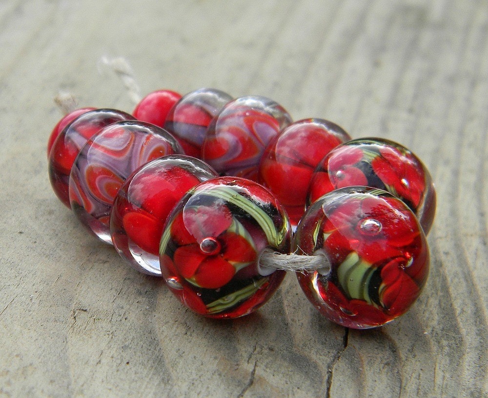 made using cherry red and purple glass and is composed of 2 free spacers, various petal and triangle encased beads and three deeply encased florals.