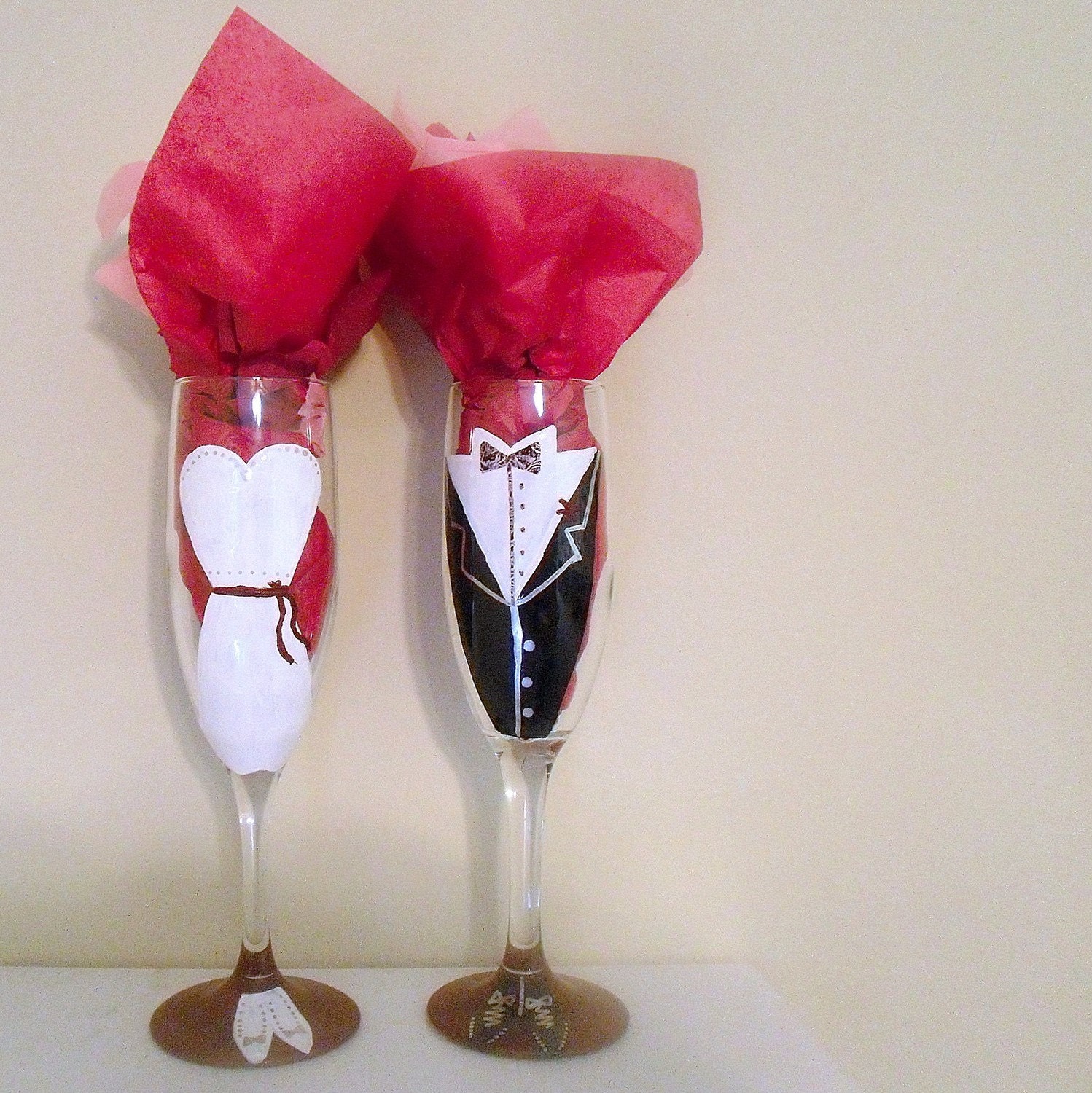 Glasses are painted with traditional wedding gear a white gown and tuxedo