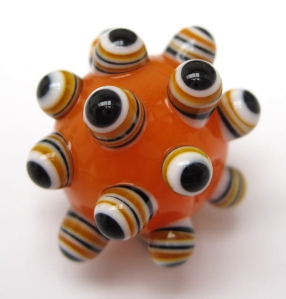 On a base of bright translucent orange there are stacked dot bumps of black, white and orange