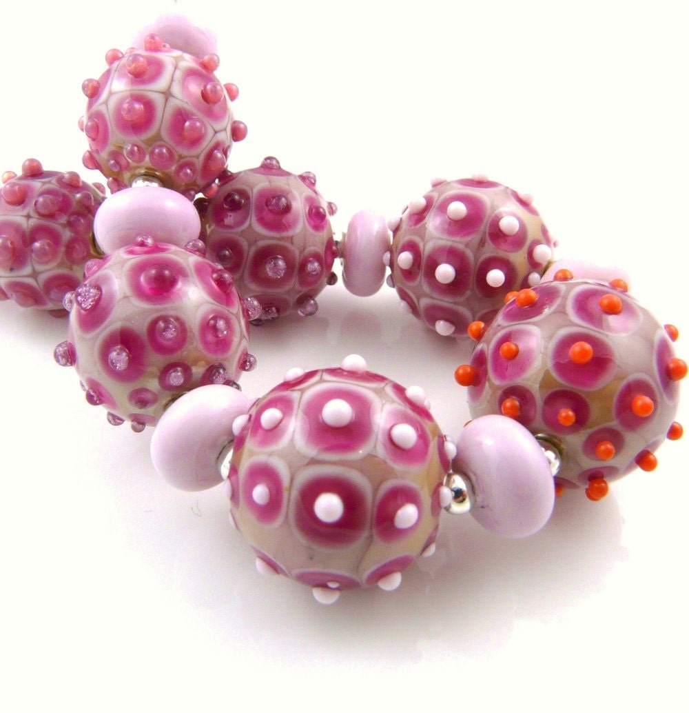 Disco Balls is a set of graduated round lampwork beads, in shades of pink with raised dots.