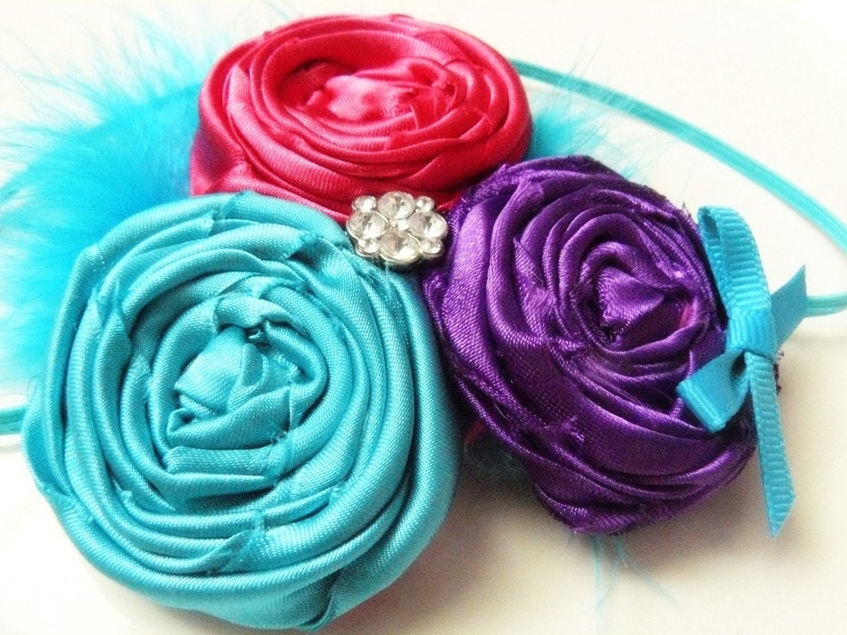 Bright and Fun. Turquoise, Hot Pink, and Vibrant Purple Rosette Trio With Center Rhinestone Accent and Added Marabou. Comes attached to a skinny turquoise headband.