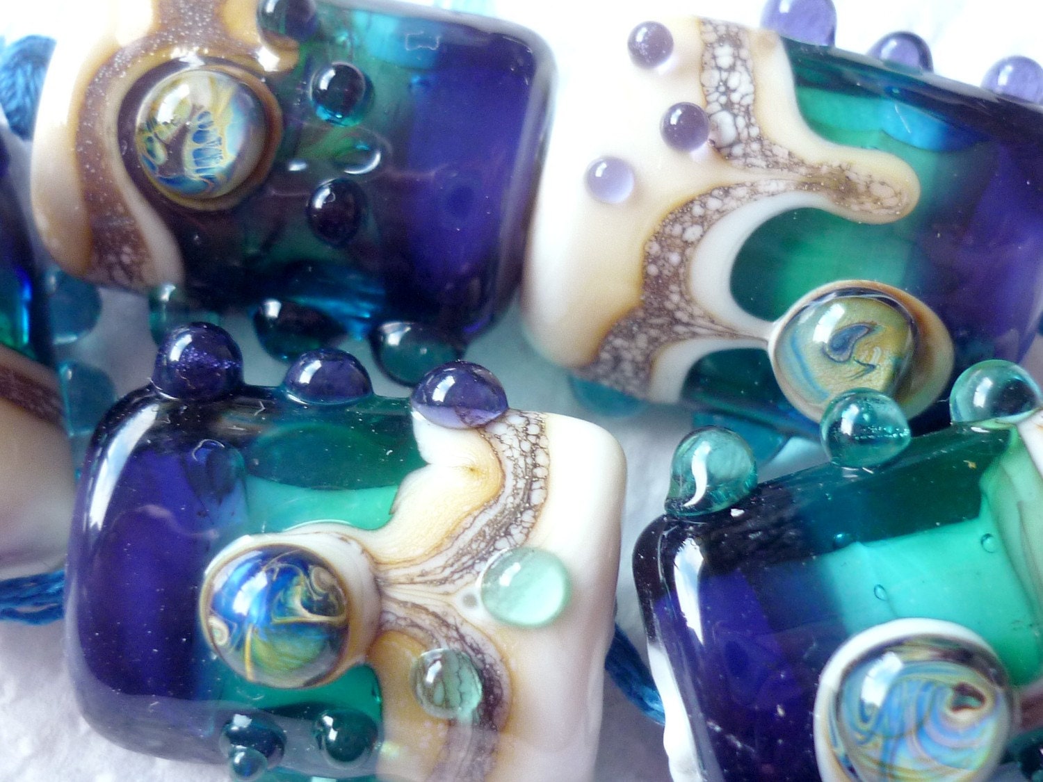 sleek pillow shaped Lampwork Beads made using Pale Ivory Opaque and deep sea blues and greens