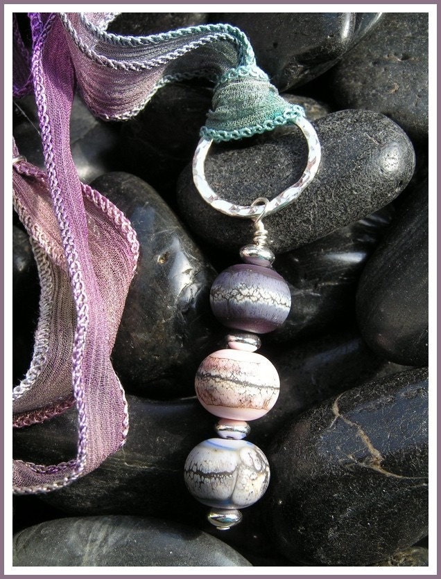 Beautiful etched beads dangling from a sterling hammered ring, worn on a hand-dyed silk ribbon